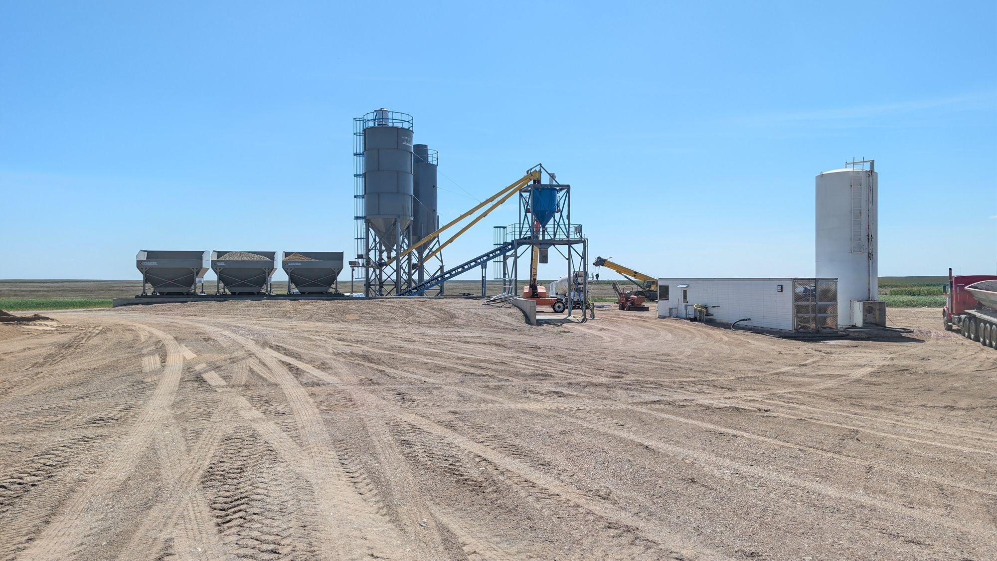 Batch plant yard with a telehandler parked by the hoppers.